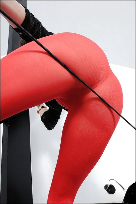 Сексуальная зрелая красотка с большими сиськами и горячей попкой позирует в красных колготках 10